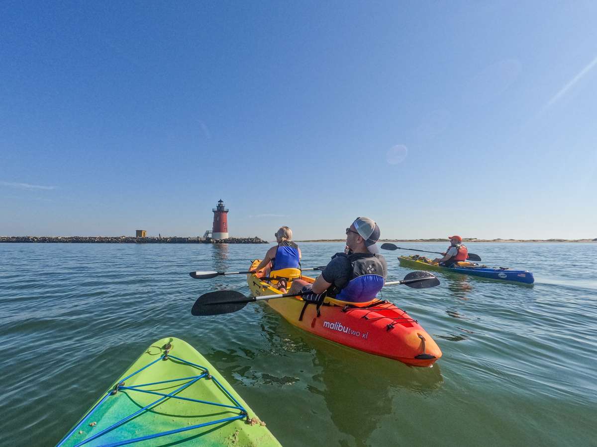 Kayakers paddling toward a lighthouse near Bethany Beach, Delaware
