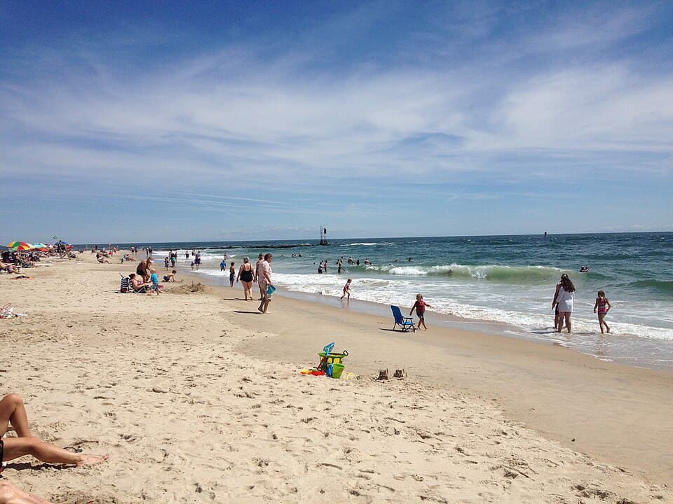 Indian River Inlet beach in Delaware Seashore State Park with families in the surf