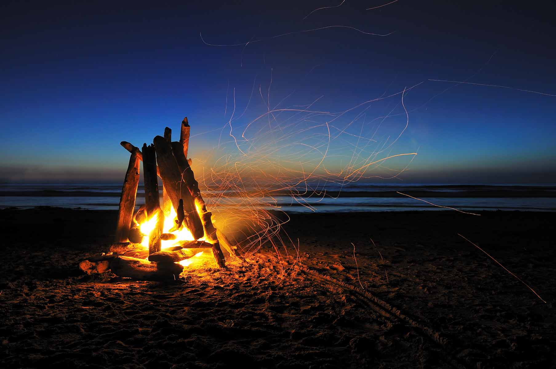 Friends enjoying a beach bonfire at dusk