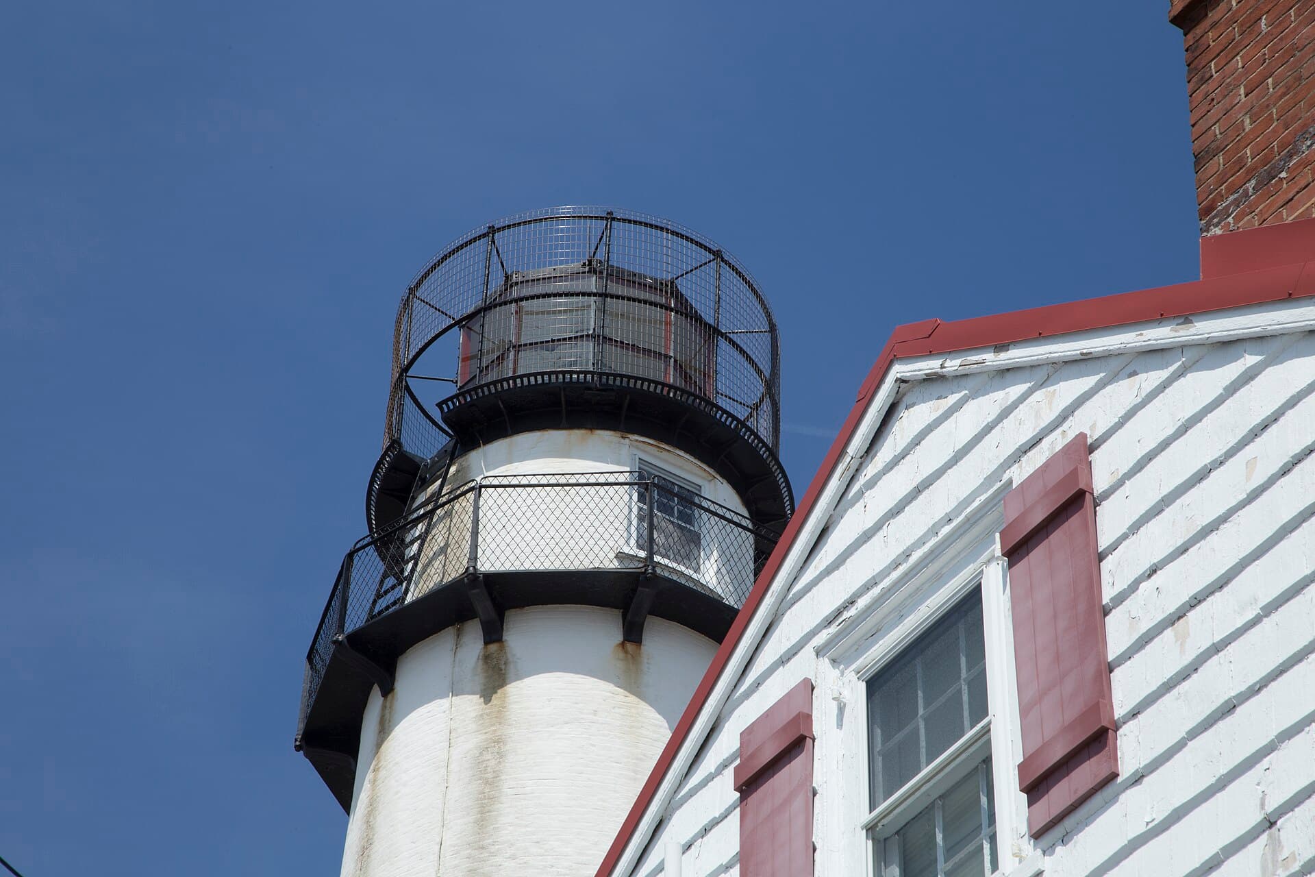 The white brick Fenwick Island Lighthouse rising beside its keeper’s house